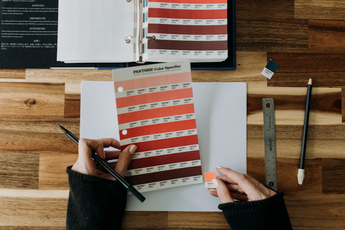a person holding a pen over a paper with a color chart on it
