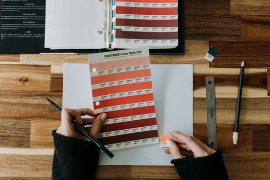a person holding a pen over a paper with a color chart on it
