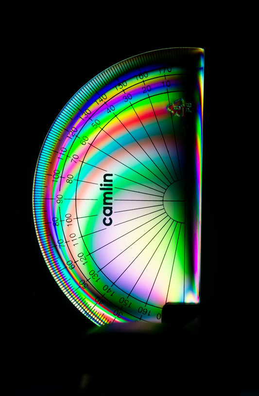 A protractor shows rainbow colors on a black background.