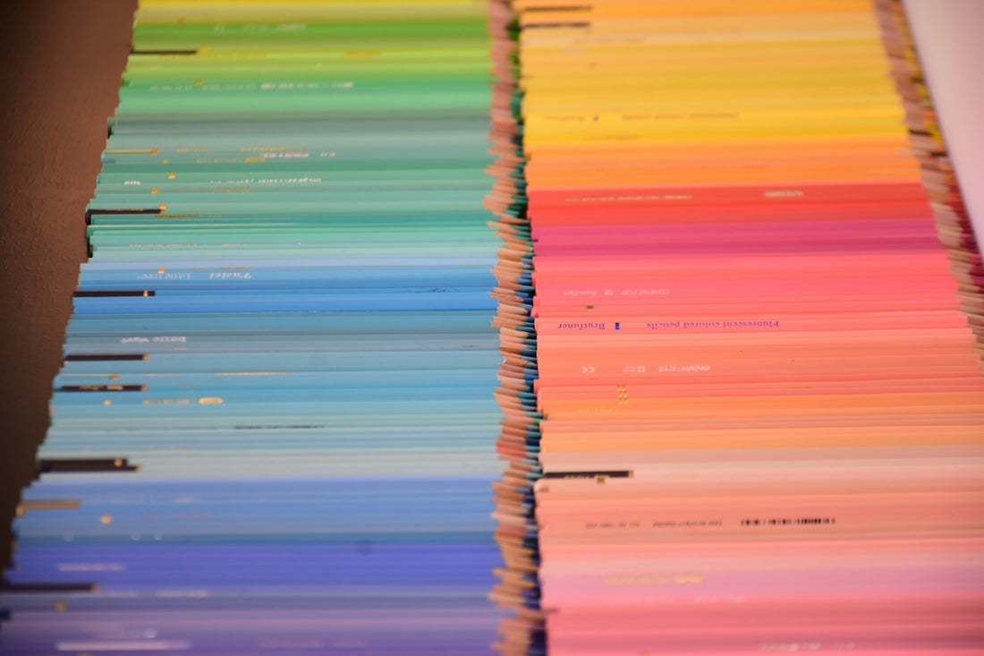 A collection of colored pencils arranged in a gradient from blue to yellow