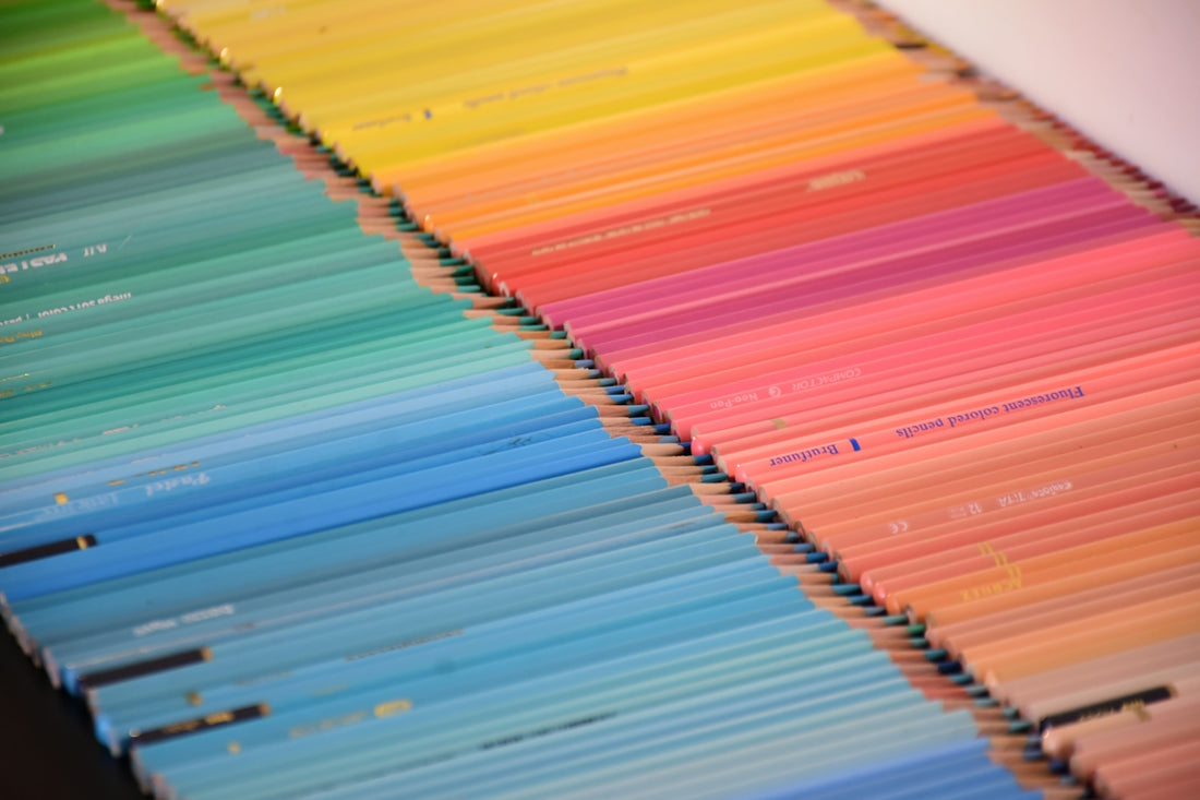 A large collection of colored pencils arranged in a vibrant rainbow gradient pattern