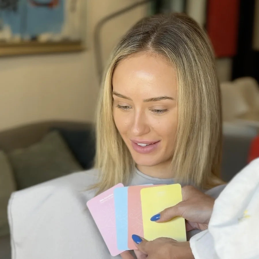 A client in a grey cape looks at four pastel Color Oracle cards held up for her to choose from
