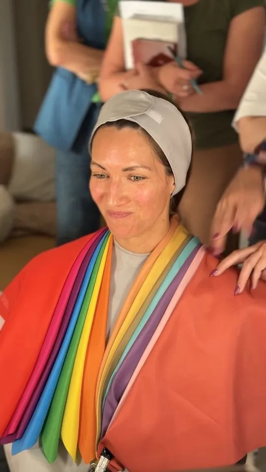 A client wearing several drapes side by side at once, so the colors can be compared on her face