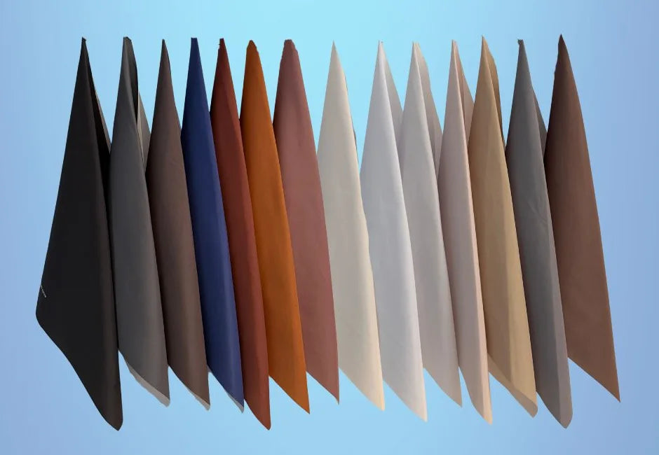 The fourteen neutral drapes hanging side by side, from black and navy to ivory and camel