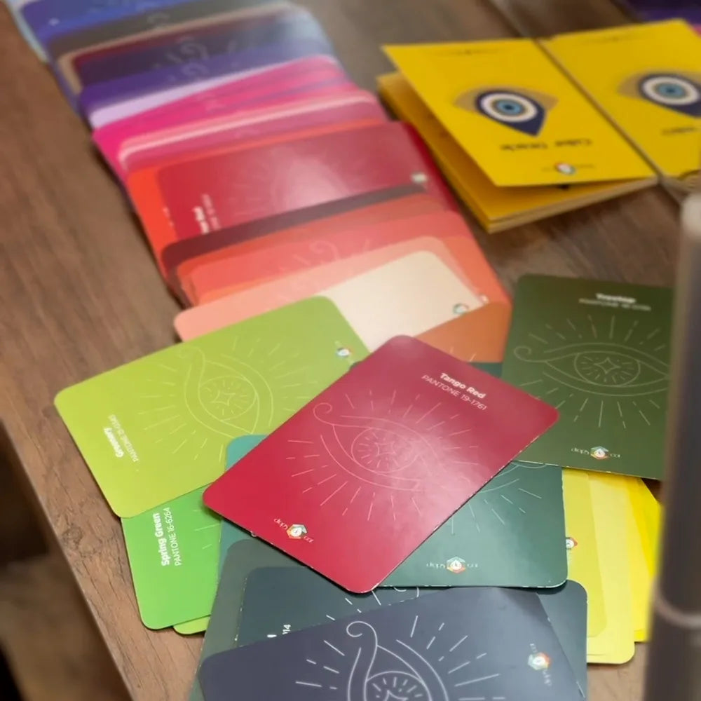 Color Oracle cards spread on a table by color family, next to yellow Color Deck booklets